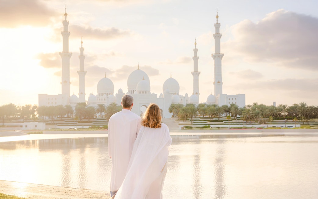 Couple viewing Sheikh Zayed Grand Mosque at sunset, Abu Dhabi.