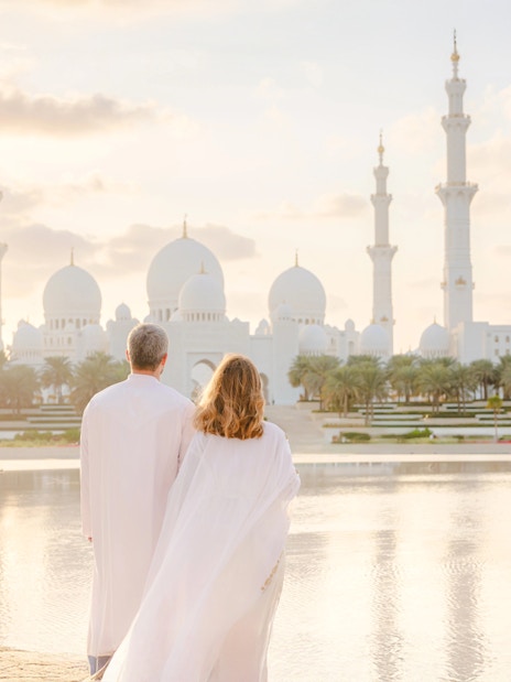 Couple viewing Sheikh Zayed Grand Mosque at sunset, Abu Dhabi.