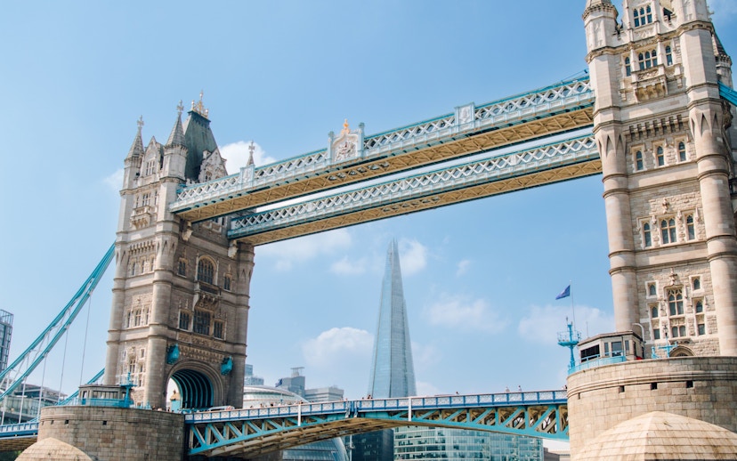 Guests on Tower of London Cruise boat passing under Tower Bridge, London.