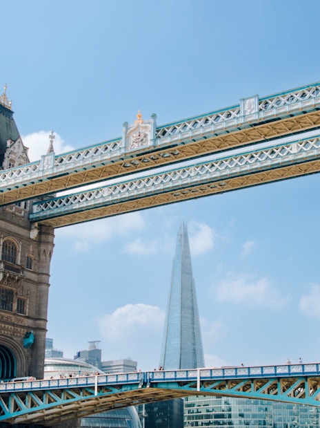 Guests on Tower of London Cruise boat passing under Tower Bridge, London.