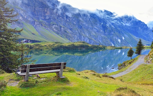 Bench overlooking Lake Trubsee with mountain reflections, Engelberg, Switzerland.