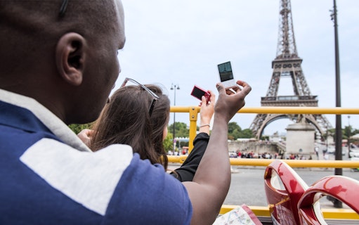 Passengers taking photos of the Eiffel Tower from a guided bus tour in Paris.