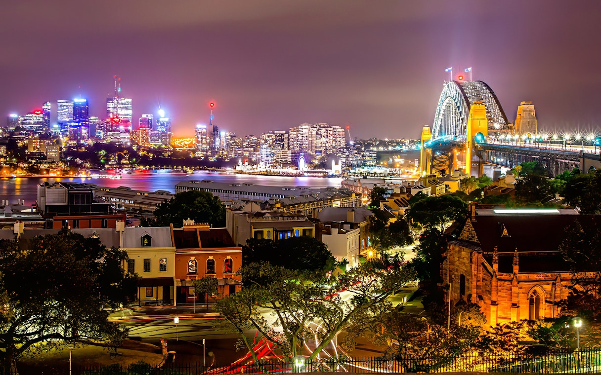 Sydney Harbour Bridge and city skyline illuminated at night during Sydney Night Tour.