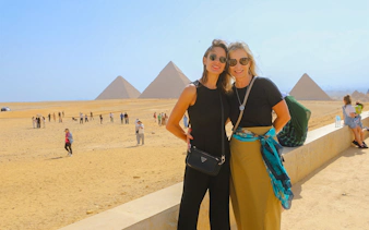 Tourists at Giza Pyramids with the Sphinx in the background, Egypt.