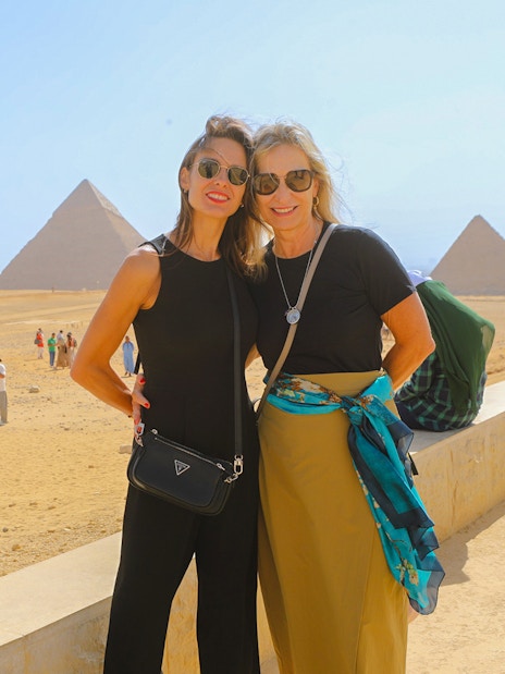 Tourists at Giza Pyramids with the Sphinx in the background, Egypt.
