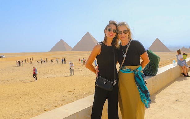 Tourists at Giza Pyramids with the Sphinx in the background, Egypt.