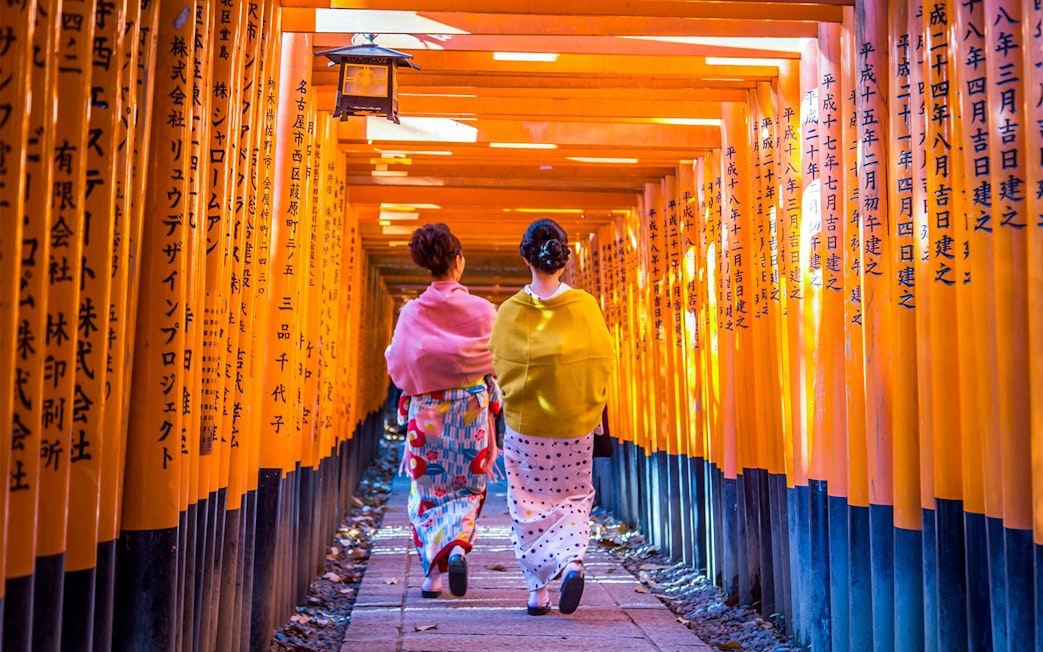 Two women walking through the torii gates at Fushimi Inari, Kyoto.