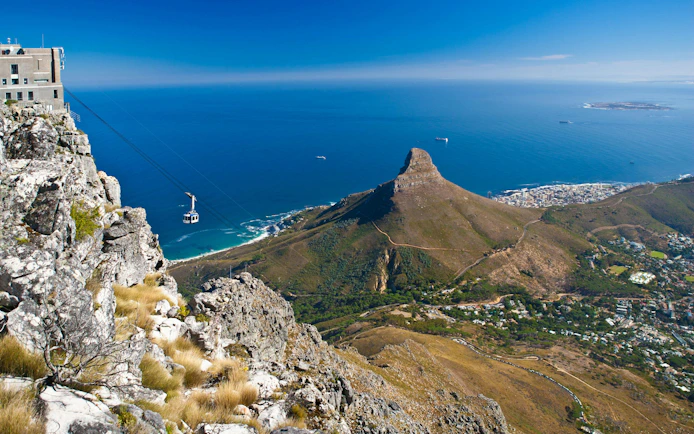 Cable car ascending Table Mountain with view of Lion's Head and Cape Town, South Africa.