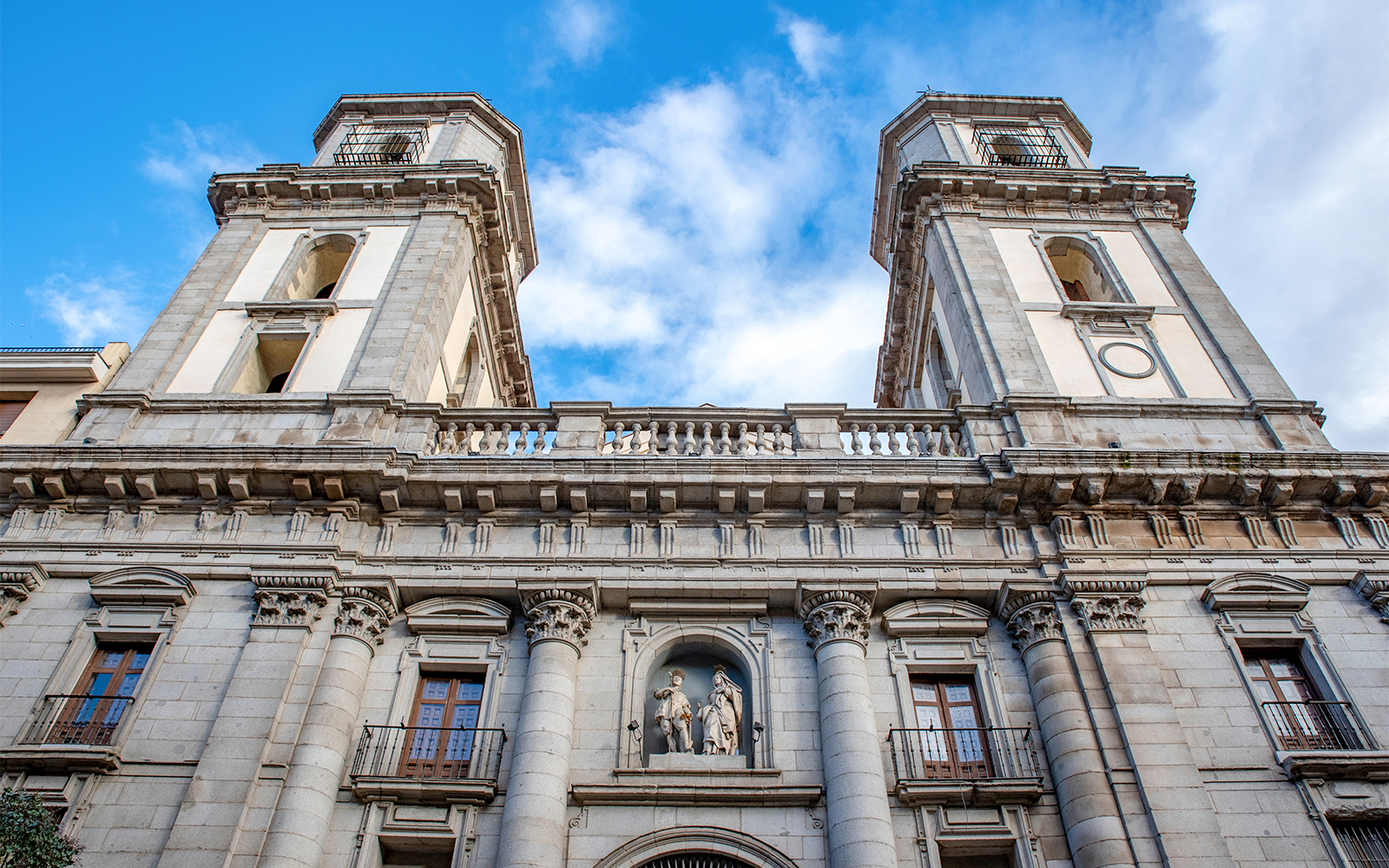 Facade of Almudena Cathedral in Madrid with twin towers and statues.