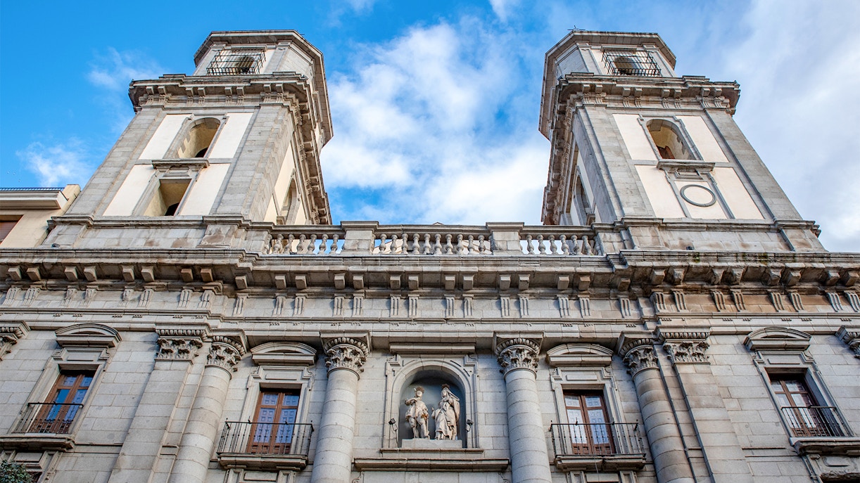 Facade of Almudena Cathedral in Madrid with twin towers and statues.