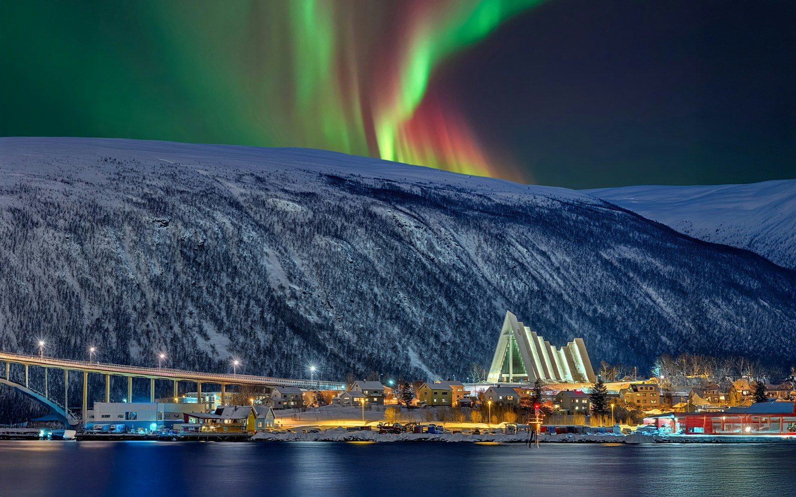 Arctic Cathedral illuminated at night with Northern Lights in Tromsø sky.