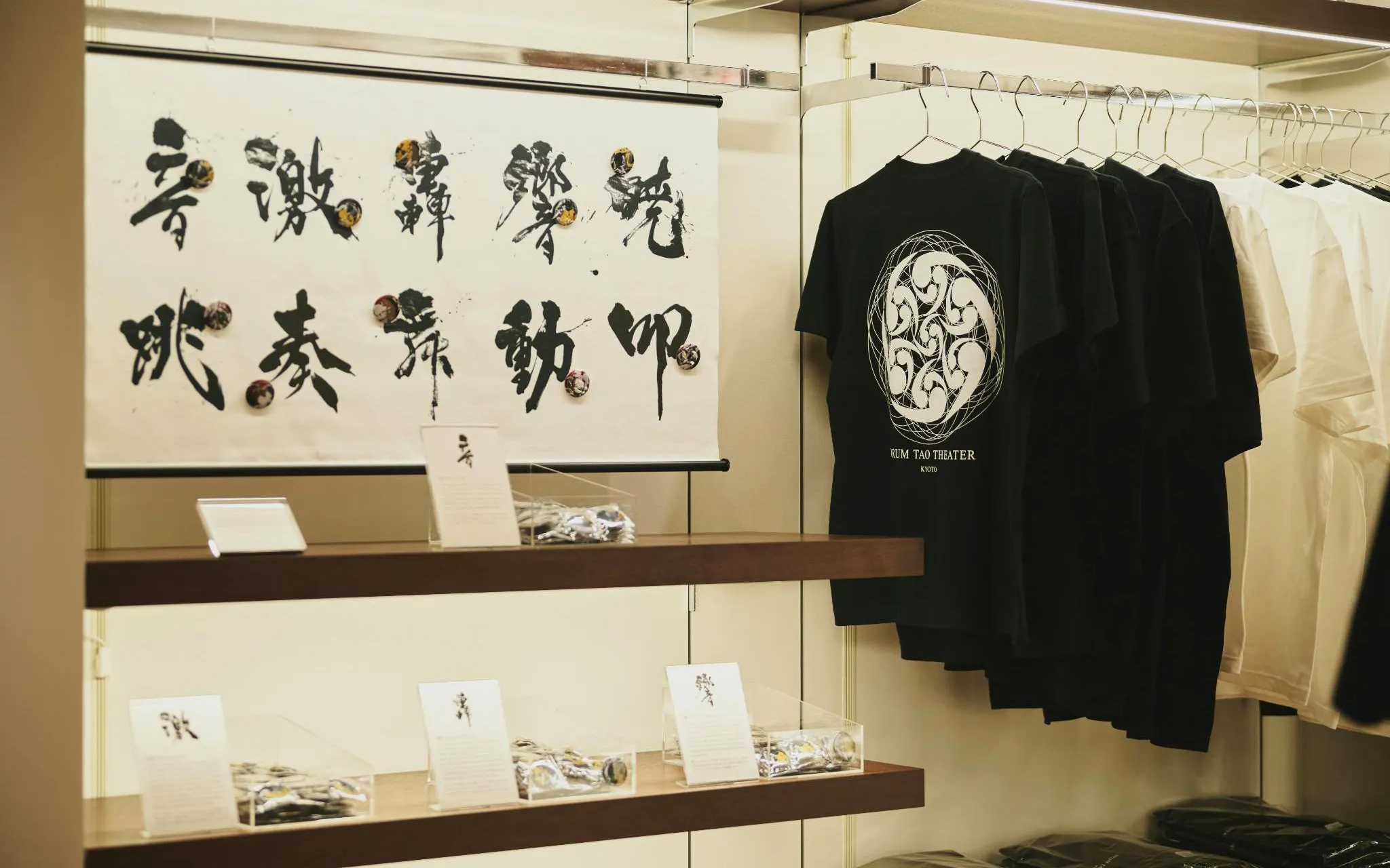 DRUM TAO Theater Kyoto merchandise display with calligraphy art and t-shirts.