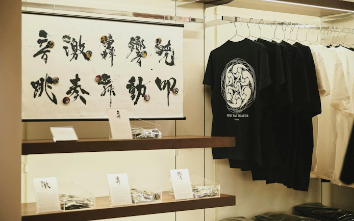 DRUM TAO Theater Kyoto merchandise display with calligraphy art and t-shirts.