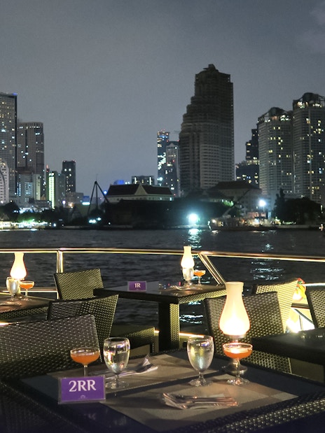 Dining setup on Chao Phraya Princess Cruise with Bangkok skyline at night.