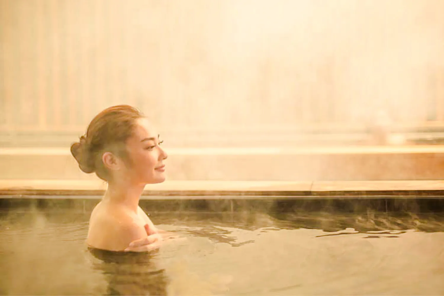 Person relaxing in a hot spring at Yunomori Onsen & Spa Sukhumvit Soi 26, Bangkok.