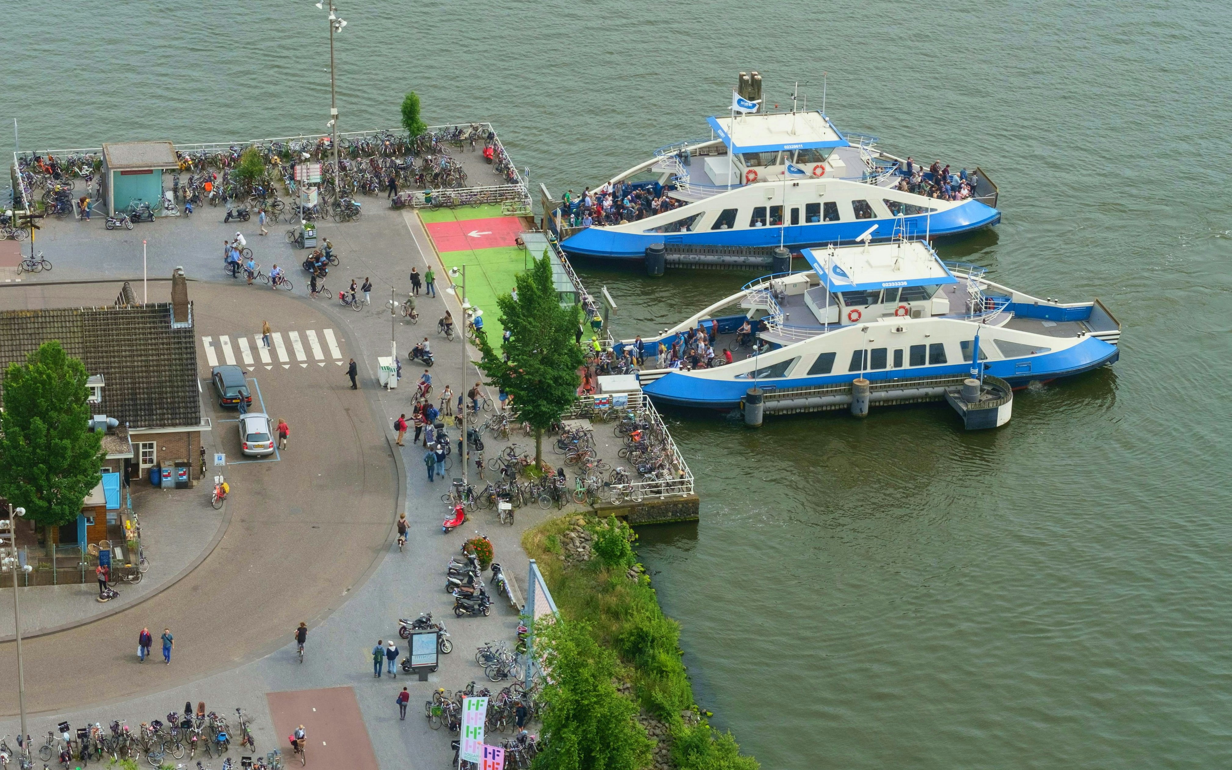 Two ferries docked at Amsterdam IJ with passengers boarding.