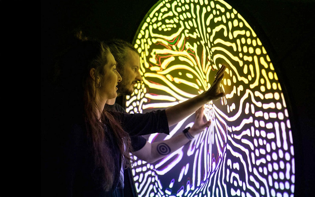 Visitors interacting with light art installation at Lumia Gallery exhibition.