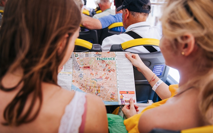 Tourists on Florence sightseeing bus holding city map.