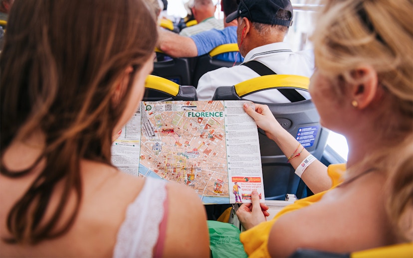 Tourists on Florence sightseeing bus holding city map.