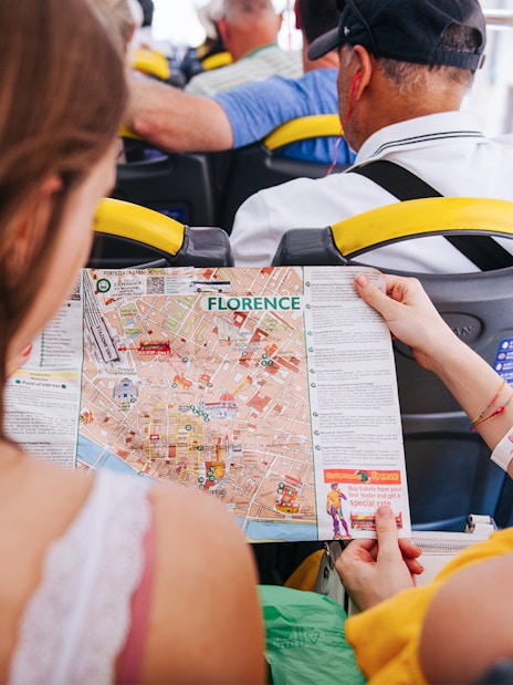 Tourists on Florence sightseeing bus holding city map.
