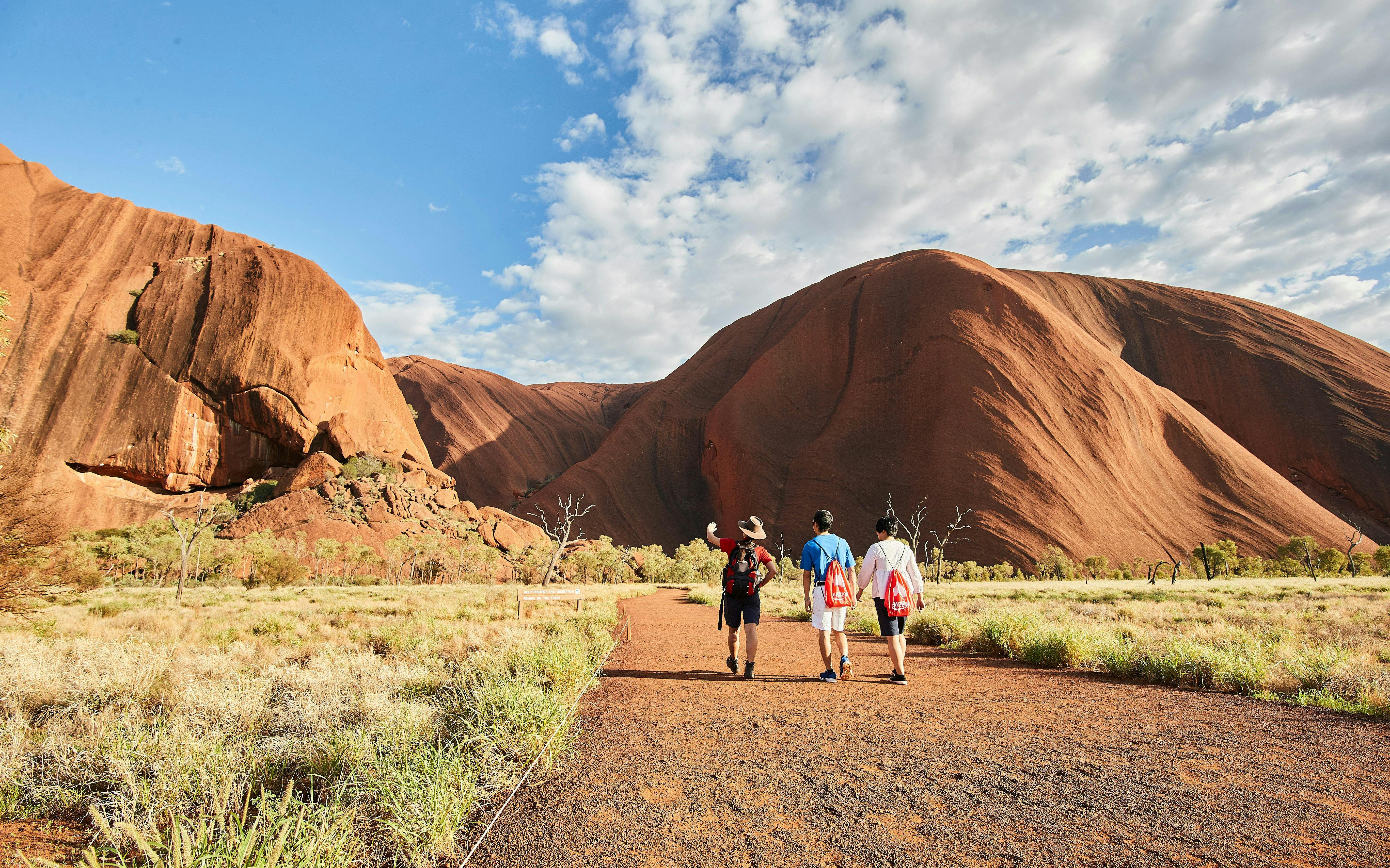 Guided group walking towards Uluru at sunrise, Australia.