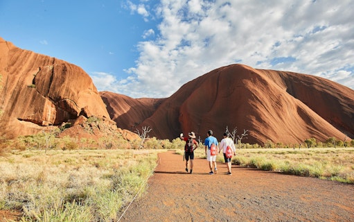 Guided group walking towards Uluru at sunrise, Australia.