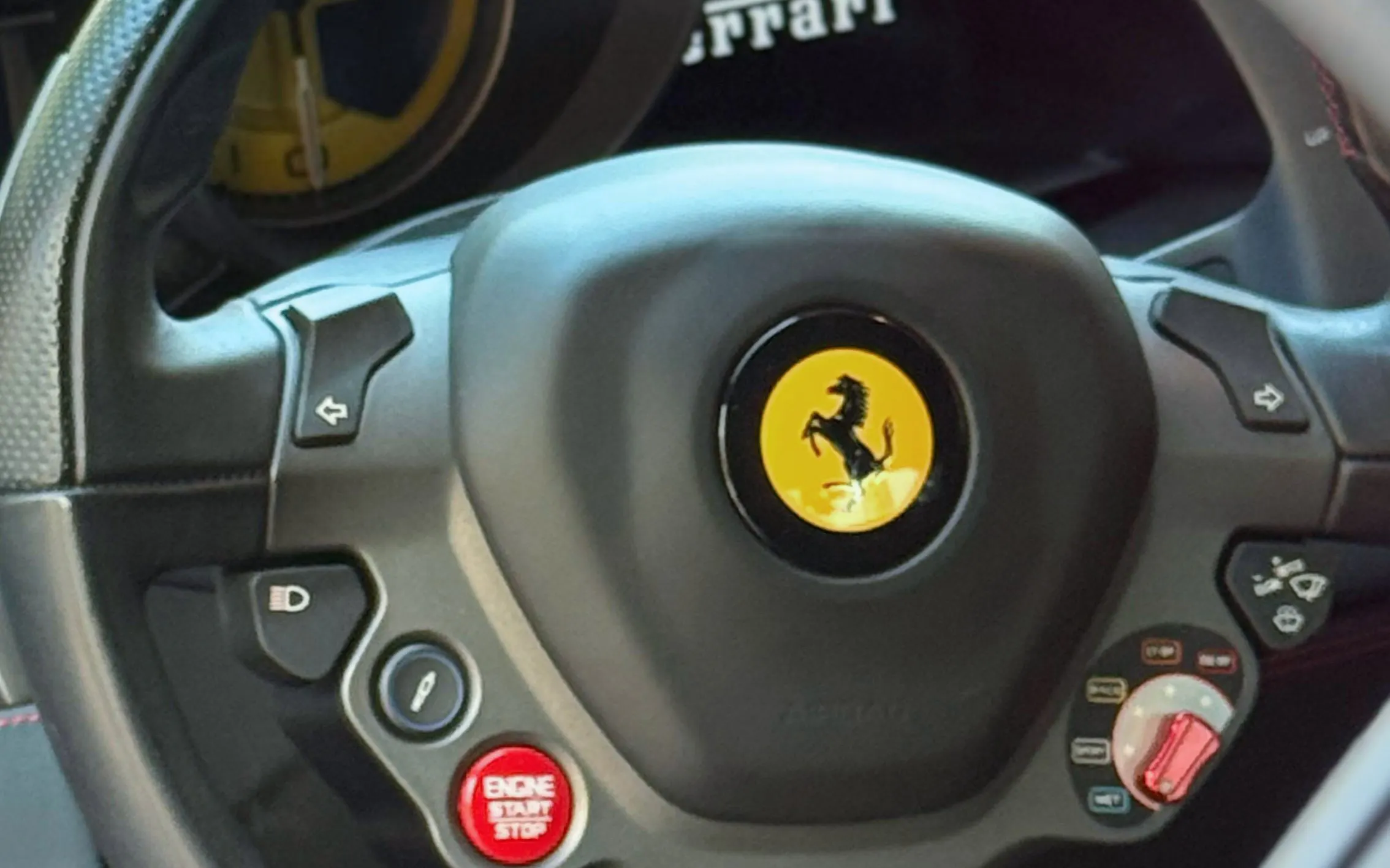 Ferrari 488 steering wheel with logo and controls.