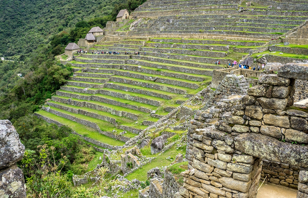 Terraced stone structures at Machu Picchu, Peru, with tourists exploring the ancient site.