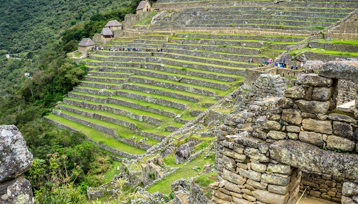 Terraced stone structures at Machu Picchu, Peru, with tourists exploring the ancient site.