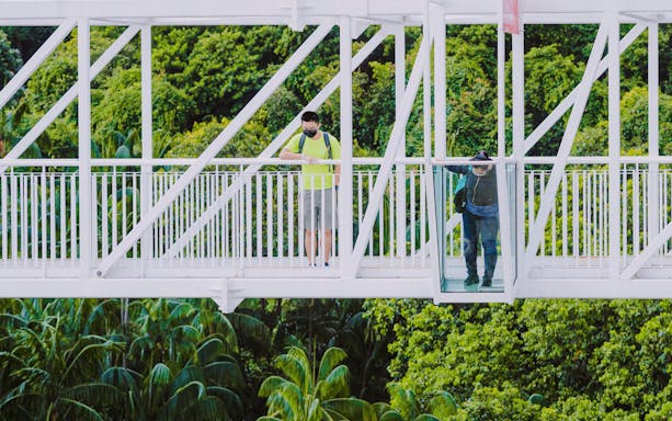 Visitors on Skybridge at AJ Hackett, Sentosa, Singapore, with lush greenery below.
