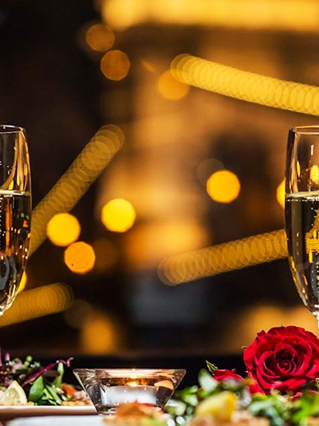 Champagne glasses and dinner setting on Budapest dinner cruise with city lights.