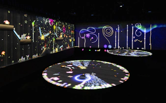 Interactive digital art exhibit with colorful projections on walls and floor.