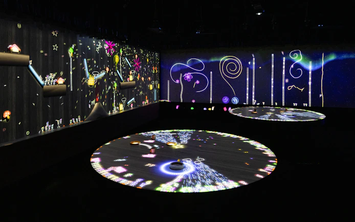 Interactive digital art exhibit with colorful projections on walls and floor.