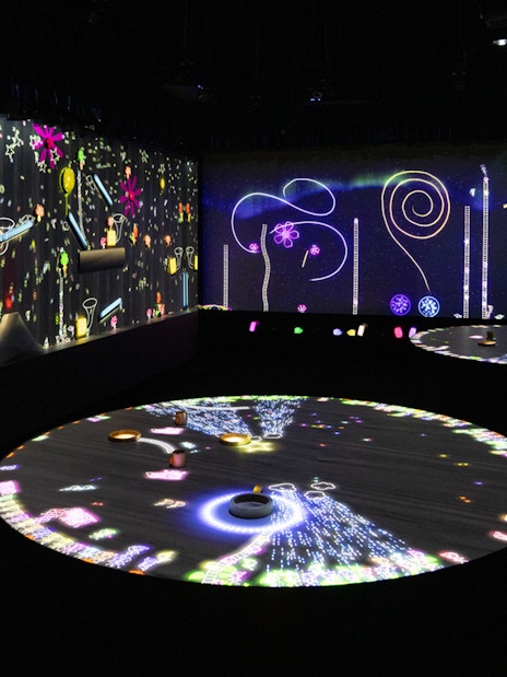 Interactive digital art exhibit with colorful projections on walls and floor.