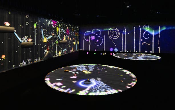 Interactive digital art exhibit with colorful projections on walls and floor.