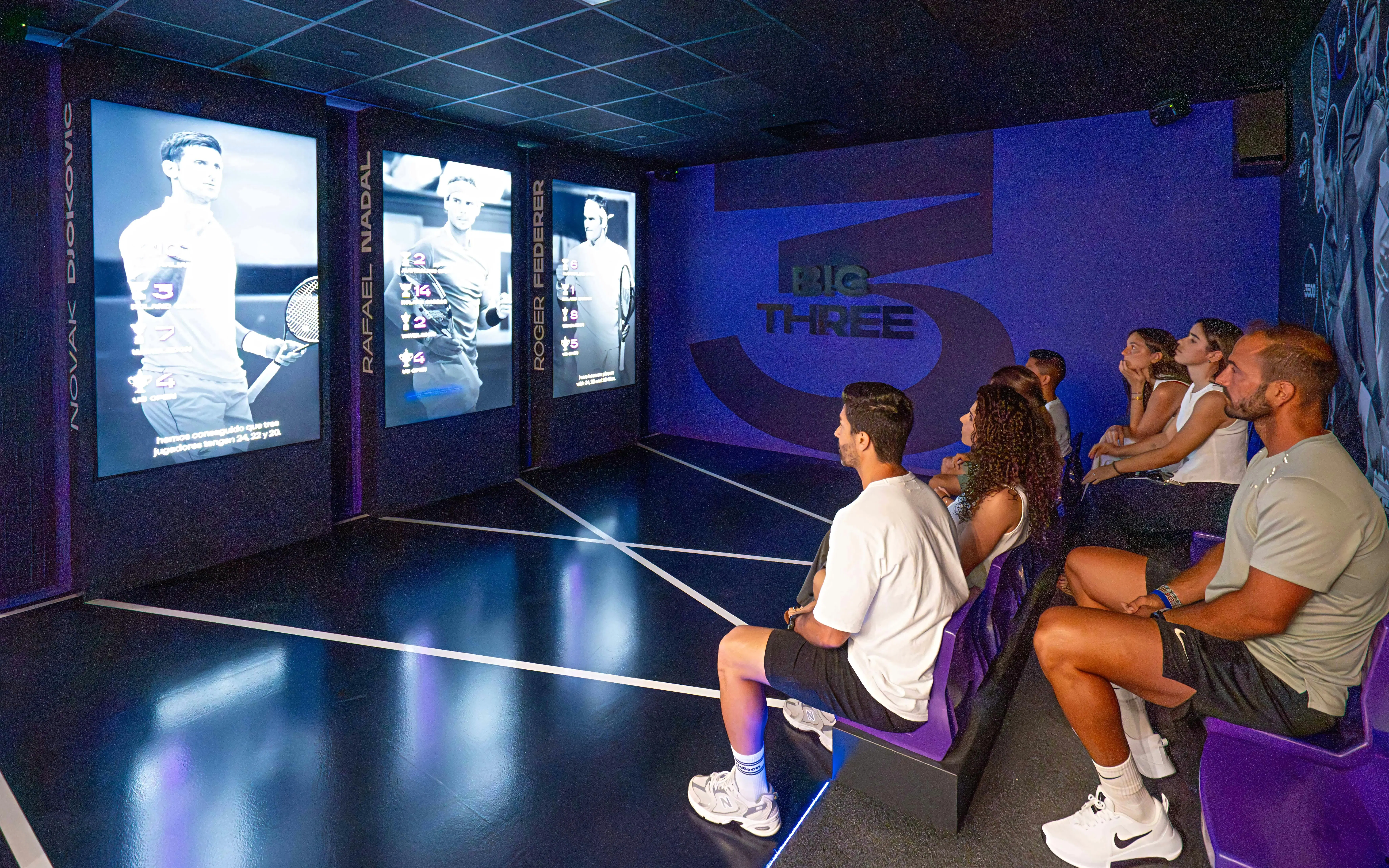 Visitors watching tennis legends exhibit at Rafa Nadal Museum.