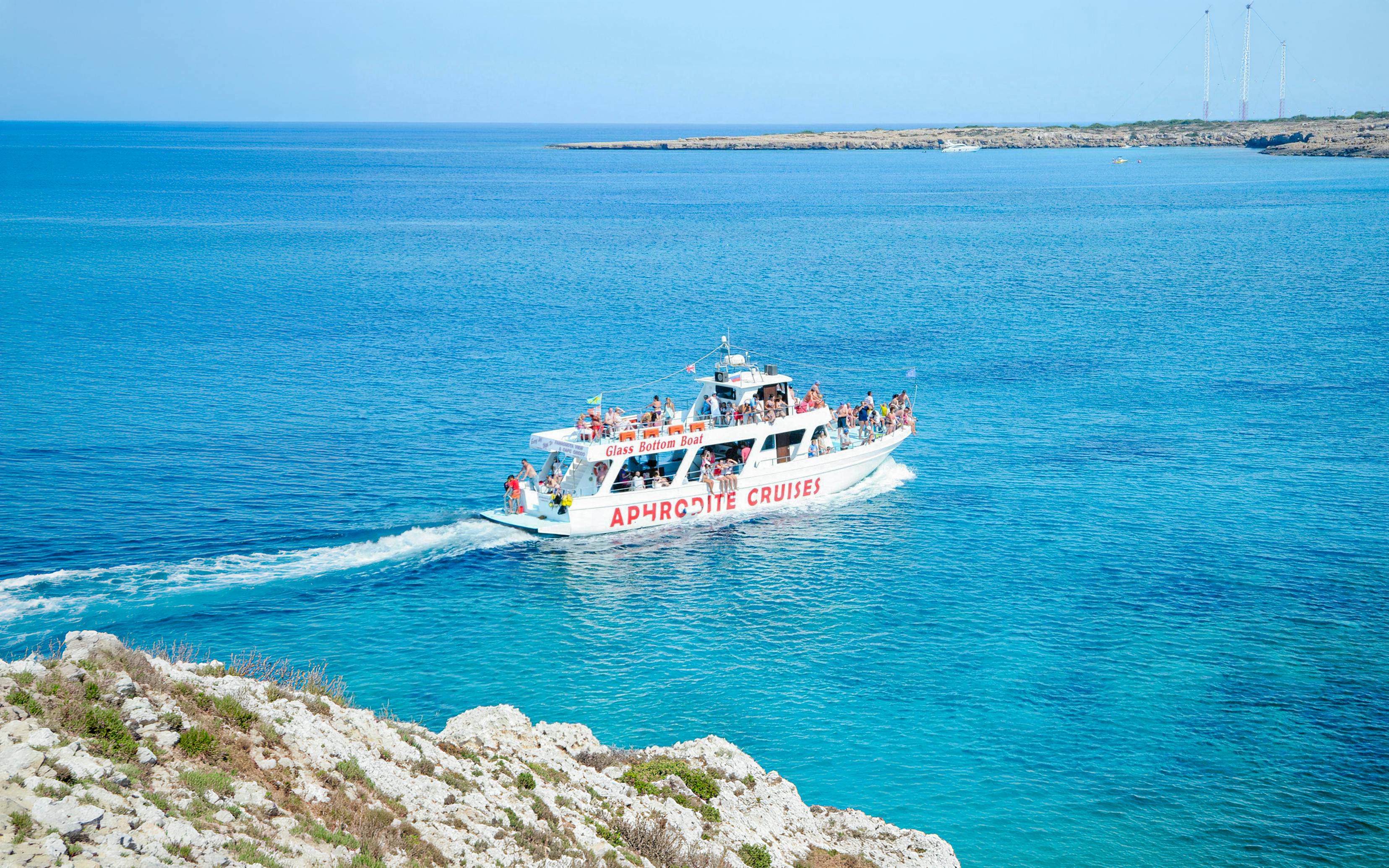 Cruise boat on Blue Lagoon waters near Protaras, Cyprus, with passengers enjoying the view.