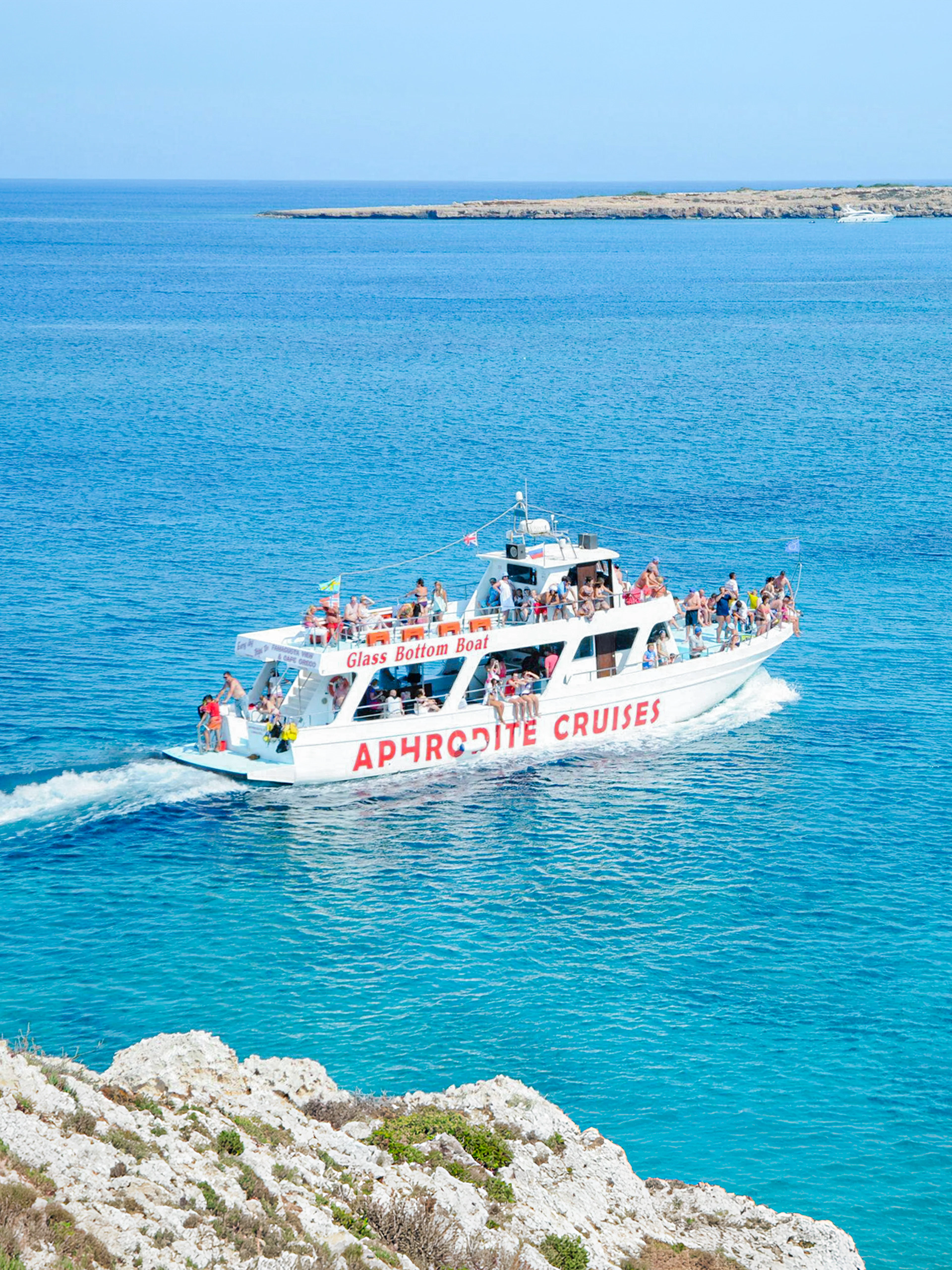 Cruise boat on Blue Lagoon waters near Protaras, Cyprus, with passengers enjoying the view.
