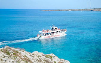 Cruise boat on Blue Lagoon waters near Protaras, Cyprus, with passengers enjoying the view.