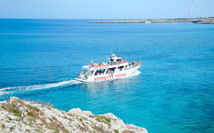 Cruise boat on Blue Lagoon waters near Protaras, Cyprus, with passengers enjoying the view.