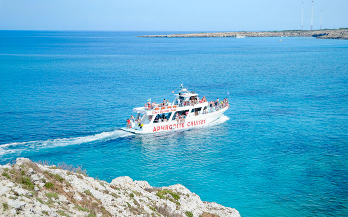 Cruise boat on Blue Lagoon waters near Protaras, Cyprus, with passengers enjoying the view.