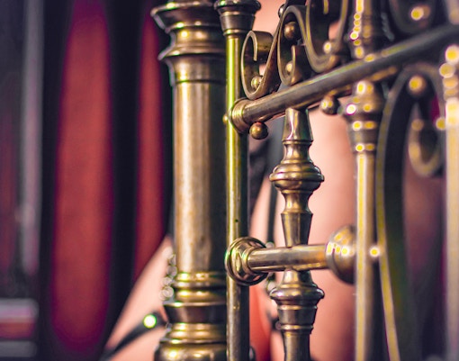 Ornate brass bed frame detail in a vintage bedroom setting.