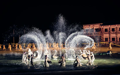 Performers in traditional attire during Hoi An Memories Show, Vietnam, with water effects and historical backdrop.