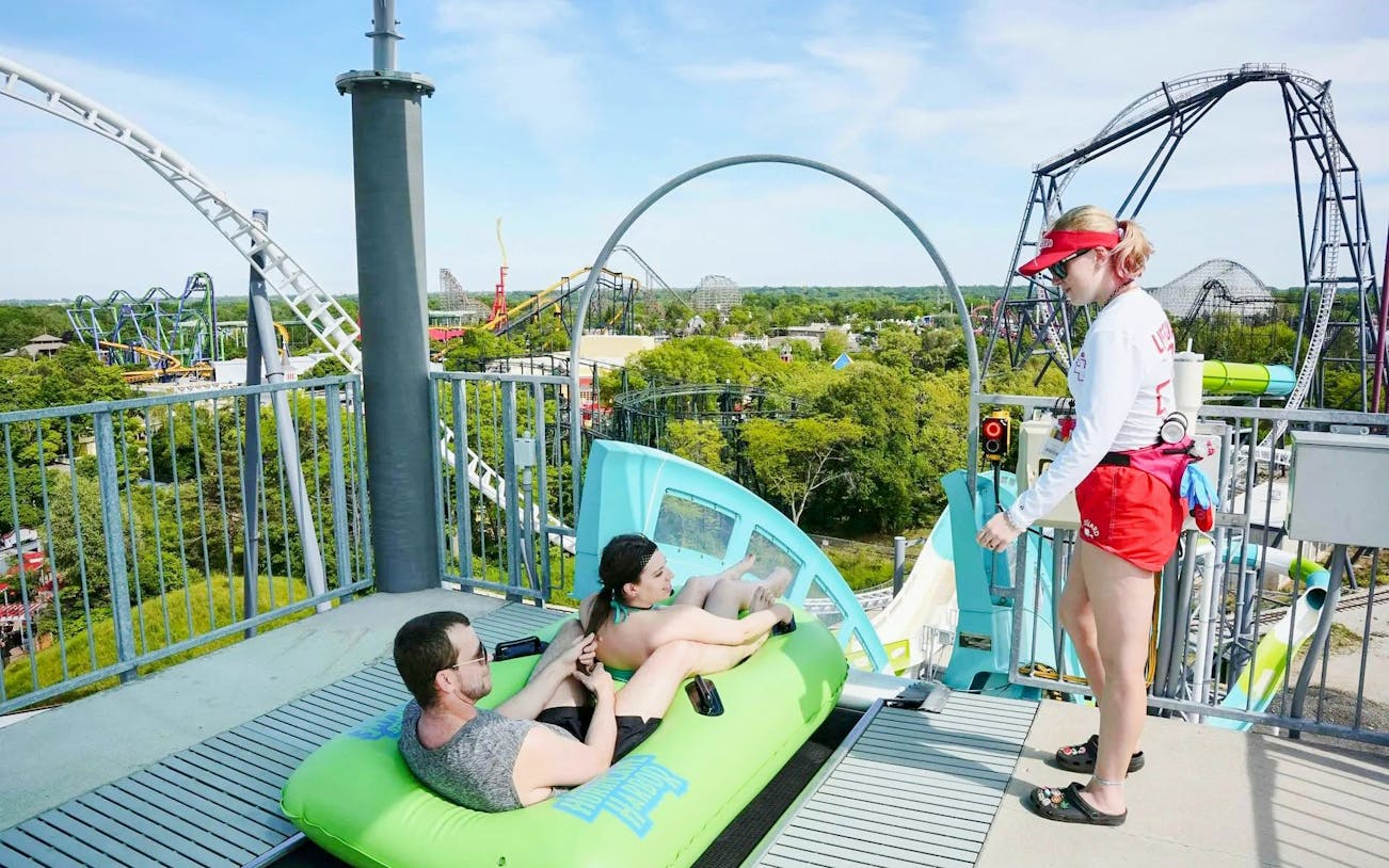 Visitors on a water slide at Hurricane Harbor Chicago with a lifeguard nearby.