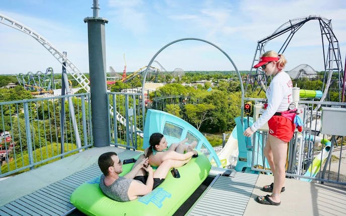 Visitors on a water slide at Hurricane Harbor Chicago with a lifeguard nearby.