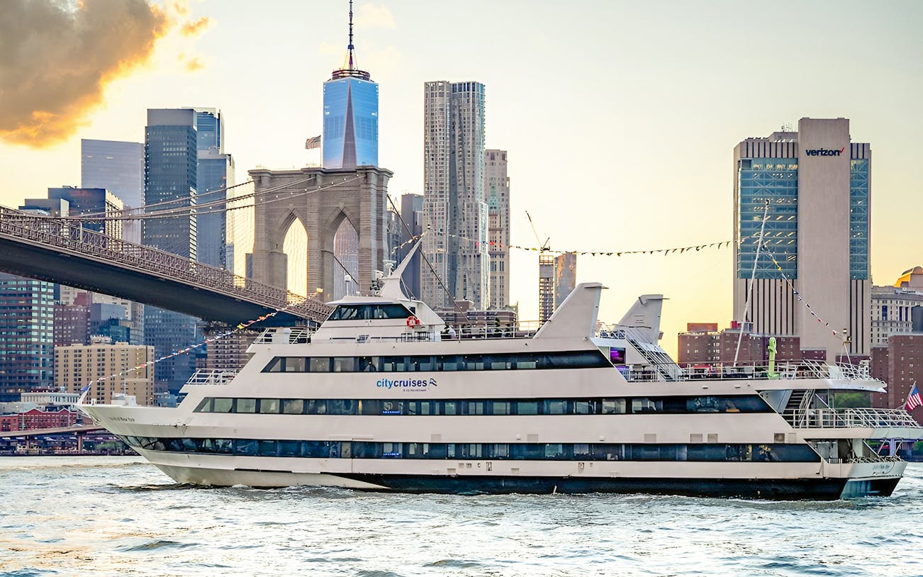 Cruise ship sailing near Brooklyn Bridge with New York City skyline in the background.