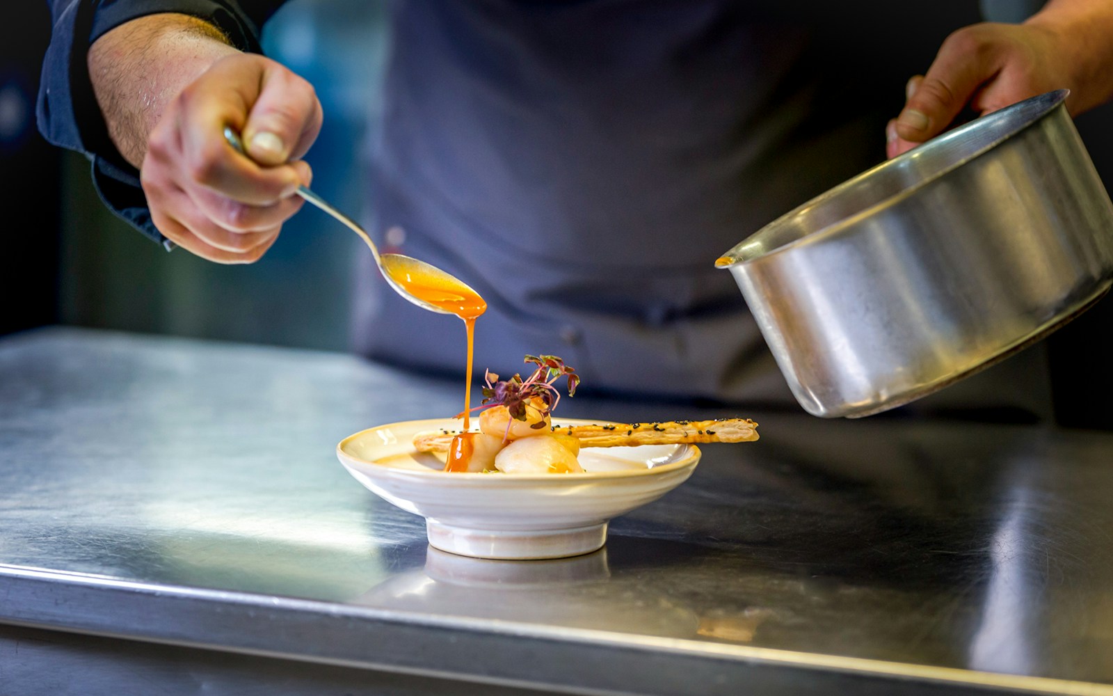 Chef pouring gravy over a dish