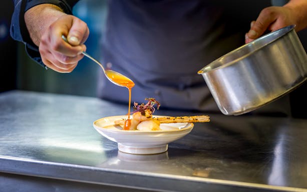 Chef preparing gourmet dish on La Marina dinner cruise.