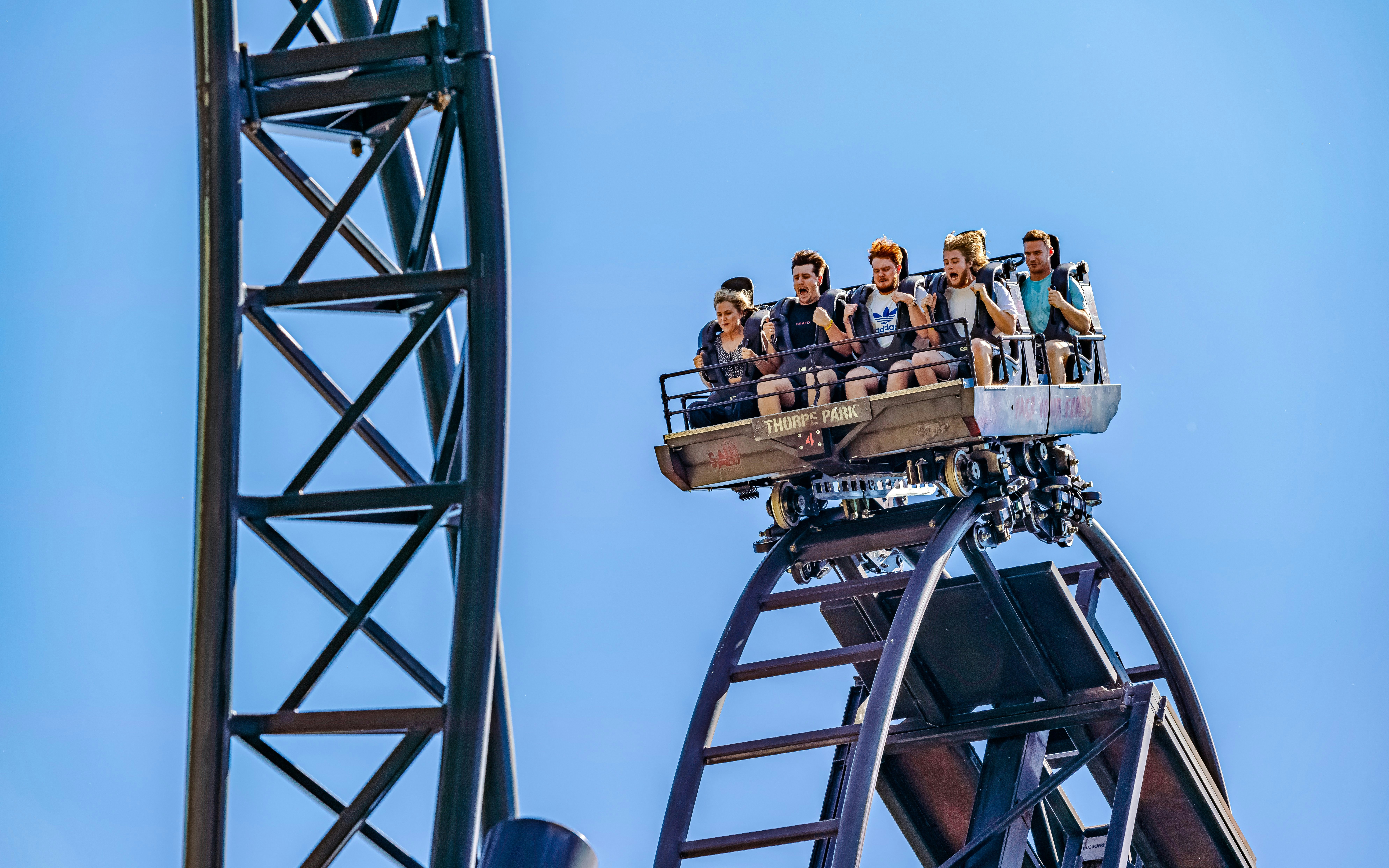 Riders on the SAW roller coaster at Thorpe Park, London, descending a steep track.