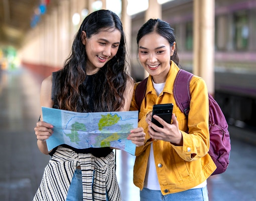 Two women examining a map for budget travel planning.